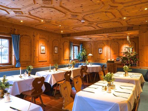 comedor con mesas y sillas y ropa de cama blanca en Hotel Hubertus Schliersee en Schliersee