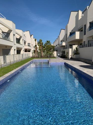 a swimming pool in front of some apartment buildings at Apartamento con solarium Villa Amalia in Torrevieja