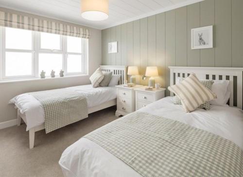 a white bedroom with two beds and a window at Swanage Bay View Resort in Langton Matravers