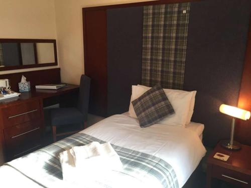 a hotel room with a bed with a desk and a mirror at Polochar Inn in Lochboisdale