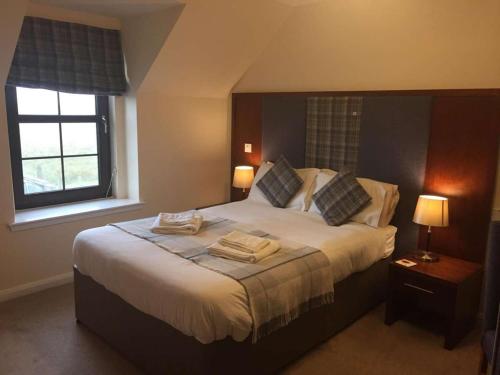 a bedroom with a large bed with two towels on it at Polochar Inn in Lochboisdale