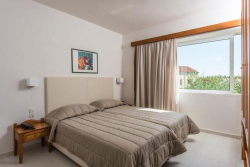 a bedroom with a bed and a large window at Stefan Village Hotel in Agia Marina Nea Kydonias