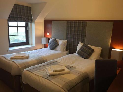 two beds in a hotel room with towels on them at Polochar Inn in Lochboisdale