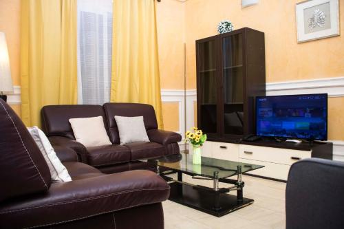 a living room with two leather chairs and a television at RÉSIDENCE DOLCE VITA - BONANJO in Douala