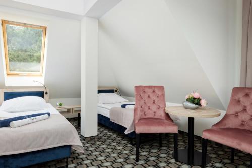 a hotel room with two beds and a table and chairs at Villa Solaris in Pobierowo