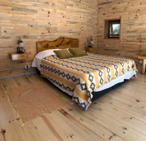 a bedroom with a bed in a wooden cabin at Wau Purul, Cabaña 2 in Cholila