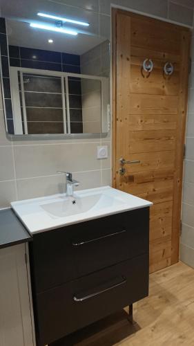 een badkamer met een wastafel en een houten deur bij Chalet des Plans in Valloire