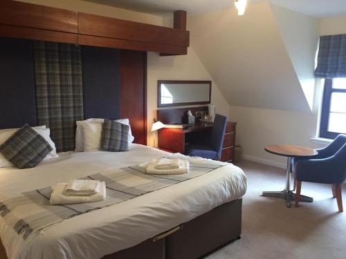 a bedroom with a large bed with a table and a chair at Polochar Inn in Lochboisdale