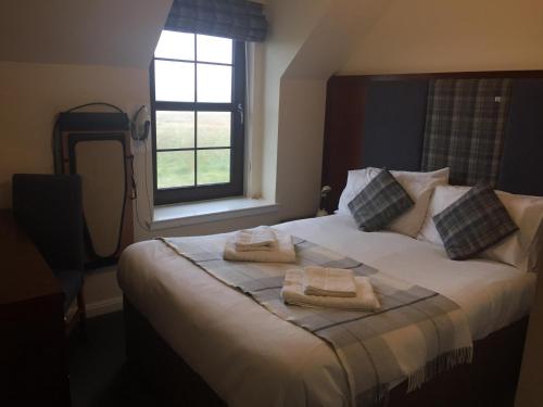 1 dormitorio con 1 cama con toallas en Polochar Inn, en Lochboisdale