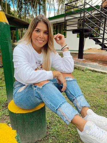 a woman sitting on a bench in the grass at Refugio El Abuelo in Santa Rosa de Cabal