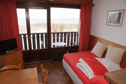 a bedroom with a bed and a balcony with a view at Studio Les Iris 18 Station Thollon les Mémises in Thollon