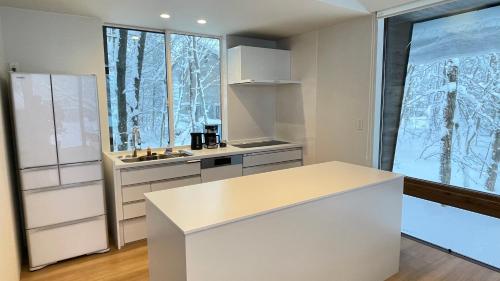 a kitchen with white counters and a large window at Ahiru Chalet by Hakuba White Fox Company in Hakuba