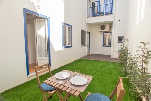 a small patio with a table and chairs on the grass at Janelas de São Bento 3 by Porto City Hosts in Porto