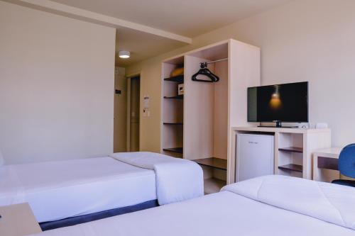 a room with two beds and a flat screen tv at Master Curitiba Hotel - 1,6 km do Estádio Couto Pereira - Show in Curitiba