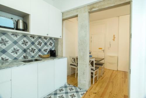 a kitchen with white cabinets and a dining room at Janelas de São Bento 3 by Porto City Hosts in Porto