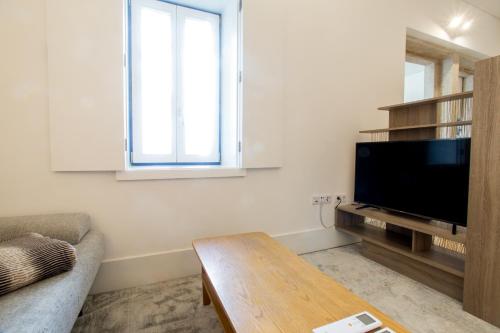 a living room with a television and a table at Janelas de São Bento 3 by Porto City Hosts in Porto