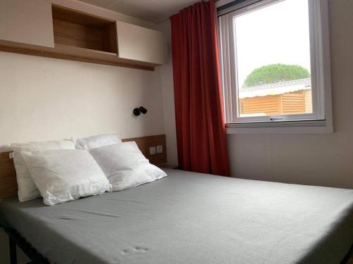 Cette chambre comprend un lit avec des oreillers blancs et une fenêtre. dans l'établissement VAM Mobil Home Mar Estang, à Canet