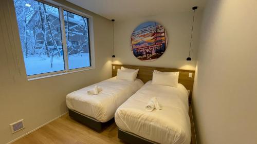 2 Betten in einem Zimmer mit 2 Fenstern in der Unterkunft Ahiru Chalet by Hakuba White Fox Company in Hakuba