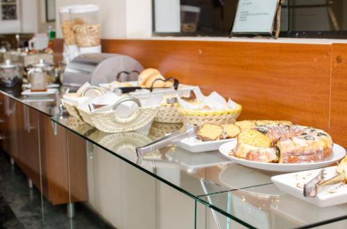 una línea de buffet con pan y bollería en una barra en Lelis Hotel, en Itapira