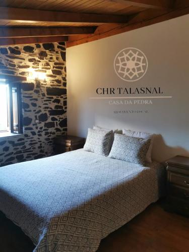a bedroom with a bed and a sign on the wall at CHR Talasnal_Casa da Pedra in Lousã