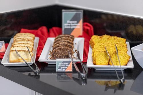 a display case with different types of cakes and desserts at Hotel Sagres Praia in Balneário Camboriú