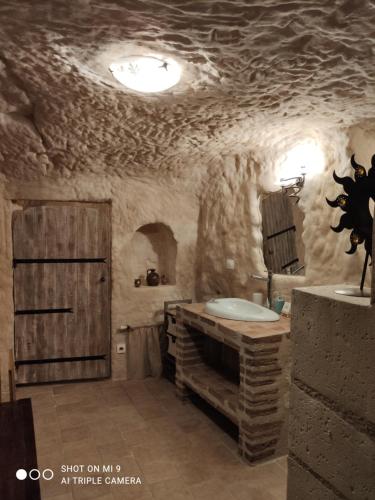 a stone bathroom with a sink and a tub at Troglodelice in Azay-le-Rideau