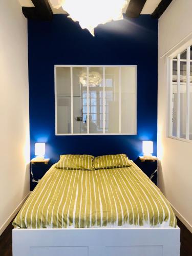 une chambre avec un lit avec un mur bleu dans l'établissement Appartement cosy en plein coeur historique, à Rouen