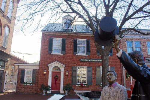 a man holding up a hat in front of a building at The Inn at Lincoln Square in Gettysburg