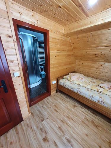 a small bedroom with a bed in a wooden cabin at Pensiunea Poarta Lui Ionele in Gîrda de Sus