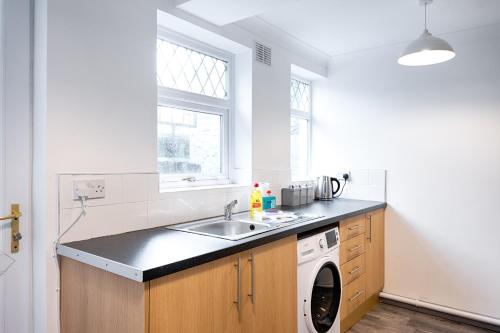 a kitchen with a sink and a washing machine at STOP at this space, near the Liberty in Swansea