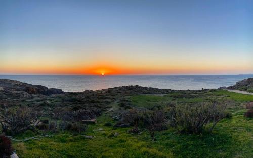 a sunset over the ocean with the sun setting at Villa Antioco in Cala Sapone
