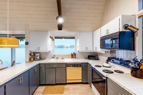 a large kitchen with white cabinets and a large window at Delake House in Otis