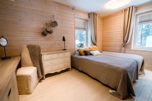 Schlafzimmer mit Holzwänden, einem Bett und einem Stuhl in der Unterkunft Mere 38 Apartments in Võsu