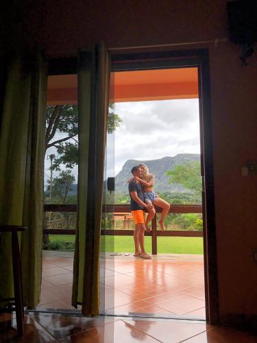 a man hugging a woman in front of a door at Pousada Bela Vista do Ismail - Lapinha da Serra in Santana do Riacho
