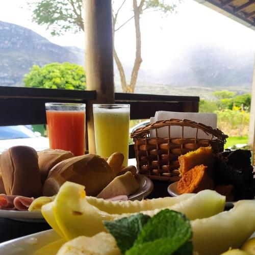 a table with a plate of food and two glasses of juice at Pousada Bela Vista do Ismail - Lapinha da Serra in Santana do Riacho