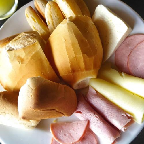 a plate of food with ham and vegetables on it at Pousada Bela Vista do Ismail - Lapinha da Serra in Santana do Riacho