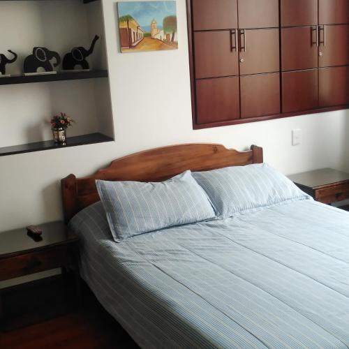 a bed with a wooden headboard in a bedroom at Posada Ventura in Duitama