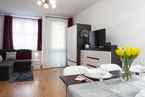 a living room with a couch and a table with yellow flowers at Luxus Apartament Alex in Gdynia