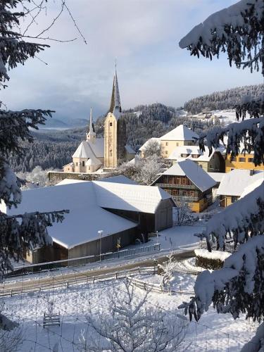 a church in the snow with snow covered buildings at Urlaub am Lacknerhof - Familie Klocker in Liebenfels