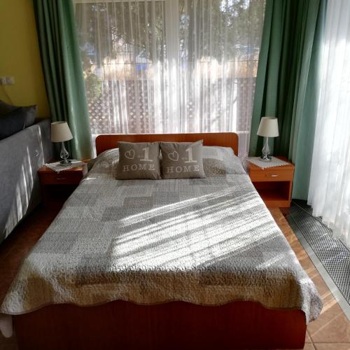 a bedroom with a bed and a window with green curtains at Bokréta Üdülő in Mezőkövesd