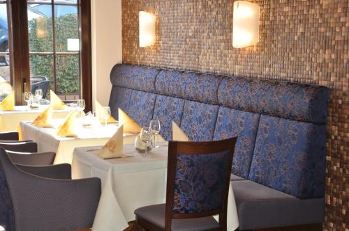 a row of tables in a restaurant with white tables and chairs at Hotel Restaurant Zum Schwan in Mettlach