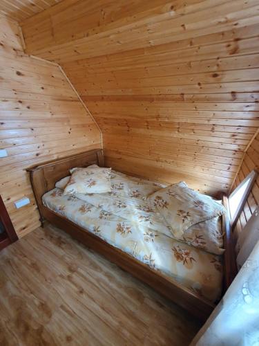 a bedroom with a bed in a wooden room at Pensiunea Poarta Lui Ionele in Gîrda de Sus