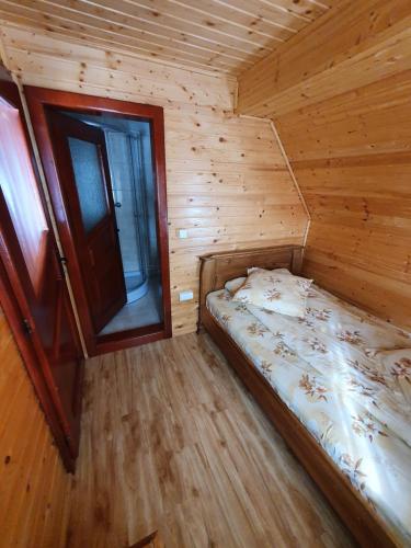 a small bedroom with a bed in a wooden cabin at Pensiunea Poarta Lui Ionele in Gîrda de Sus