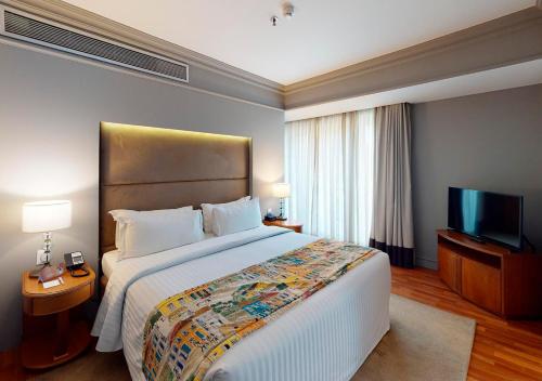 a hotel room with a large bed and a flat screen tv at Gran Estanplaza Berrini in Sao Paulo