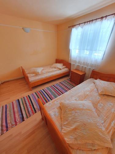 a bedroom with two beds and a rug at Pensiunea Poarta Lui Ionele in Gîrda de Sus