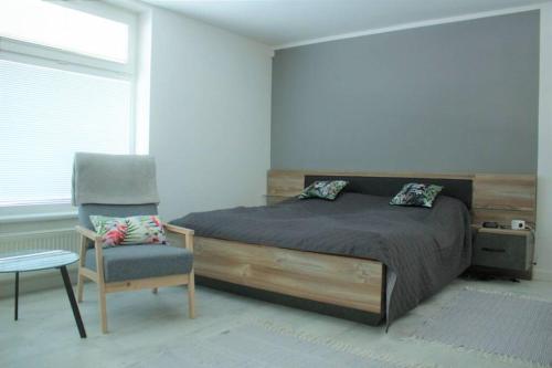 ein Schlafzimmer mit einem Bett und einem Stuhl in der Unterkunft Apartmán - Dlhé Diely in Bratislava