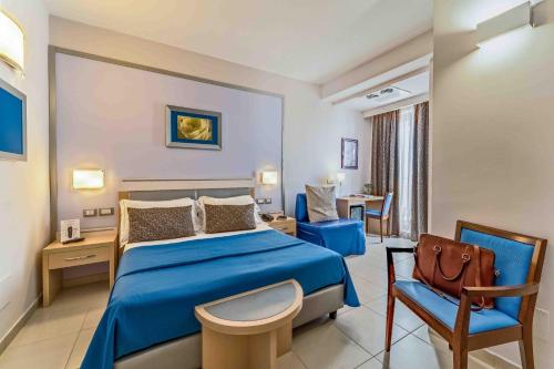 ein Hotelzimmer mit einem blauen Bett und einem Stuhl in der Unterkunft Kora Park Resort in Formia