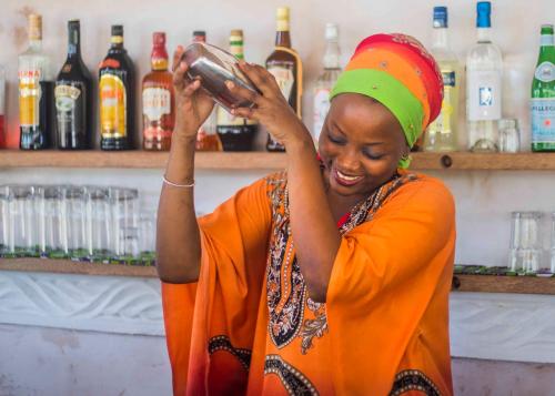 a woman in an orange outfit standing in a bar at VRclub Paje Palms Beach Resort in Paje