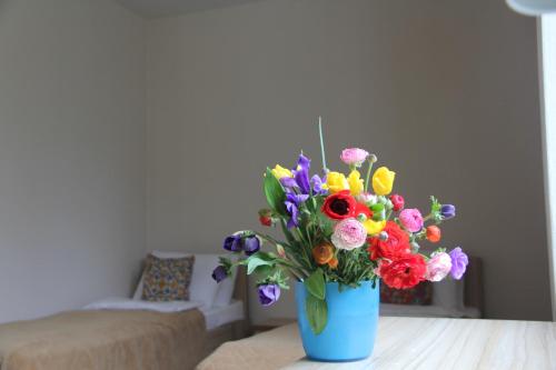 a blue vase filled with colorful flowers on a table at Apartamenty in Veseloe in Adler