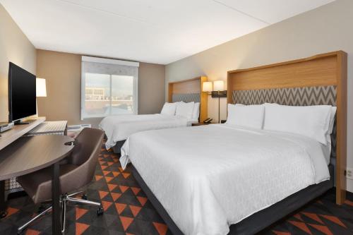 a hotel room with two beds and a desk and a computer at Holiday Inn Westbury-Long Island by IHG in Carle Place